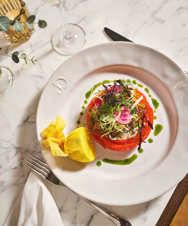 Rolled salmon gravlax topped with pea shoots and served with lemon