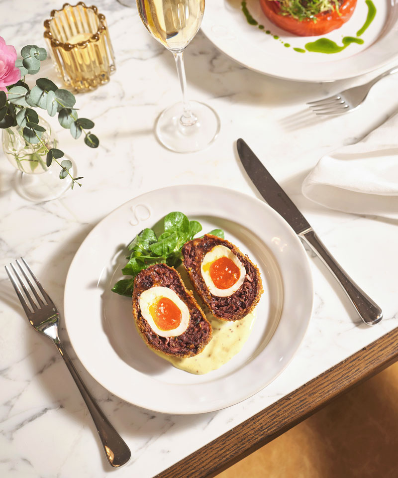 Scotch egg. Black pudding scotch egg cut in half to reveal perfect egg yolk, with a lemon dressing and pea shoot salad.